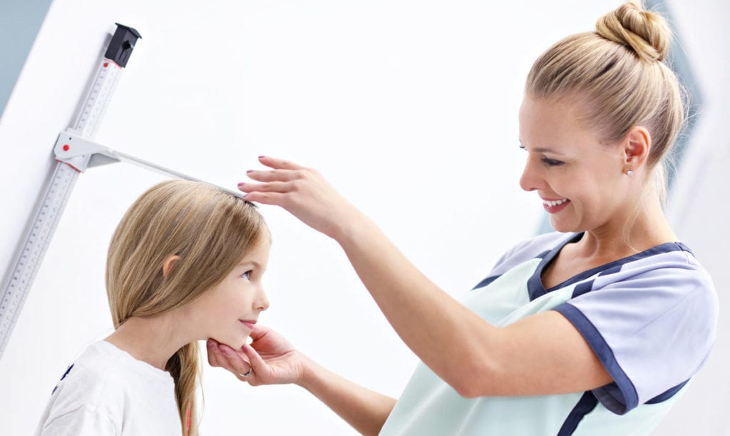 Nurse measureing the height of young girl at the pediatric endocrinologists office in Idaho Falls or Pocatello.