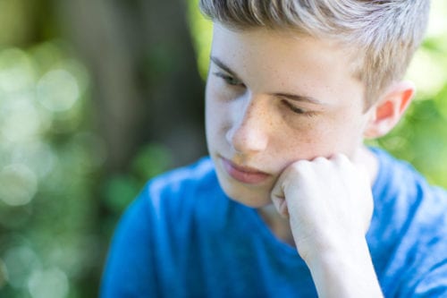 Young boy reading outside thinking about testicular dysfunction treatments by Dr. Joshua Smith, a pediatric endocrinologist in Pocatello and Idaho Falls.