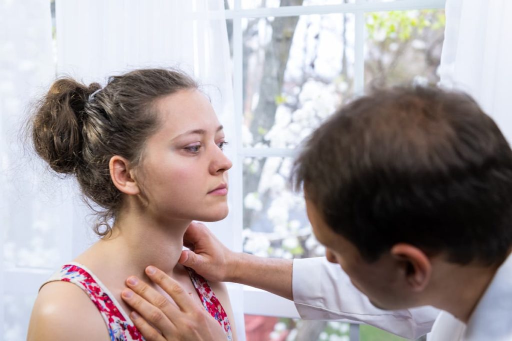 Endocrinology specialty doctor checking a patient's thyroid.