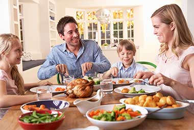 Family sitting at dinner table enjoying dinner, with parents appreciating their diabetes doctors in Idaho Falls, Pocatello, Blackfoot and all of East Idaho.
