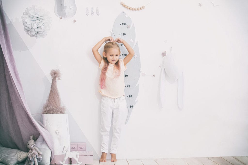 Little girl measuring herself after a short stature treatment by Dr. Joshua Smith, a pediatric endocrinologist in Pocatello and Idaho Falls.