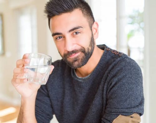 Man with a clear glass of drinking water feeling better after treatment from one of our endocrinology doctors in Idaho Falls and Pocatello.