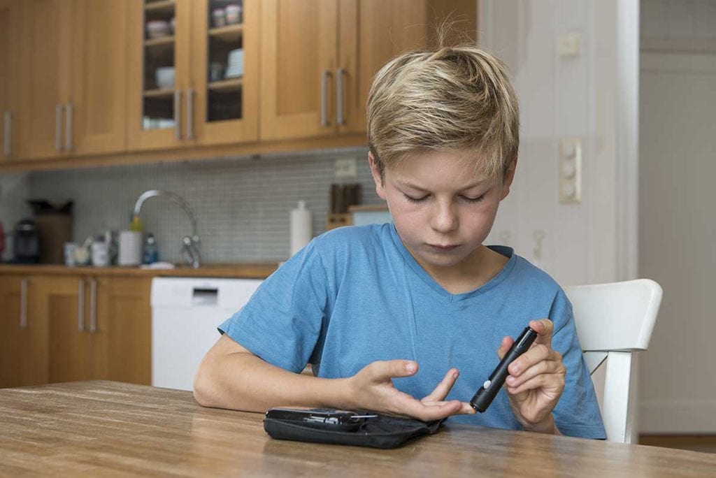 Young boy checking his blood-sugar levels with a glucometer received from Rocky Mountain Diabetes in Idaho Falls and Pocatello.