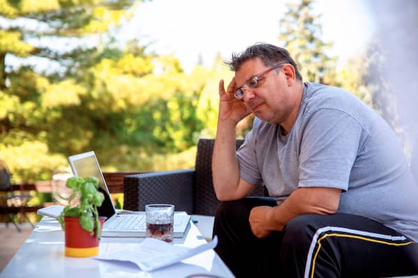 Overweight man with his laptop thinking about calling one of our endocrinology specialists in Idaho Falls or Pocatello to help with his weight gain.