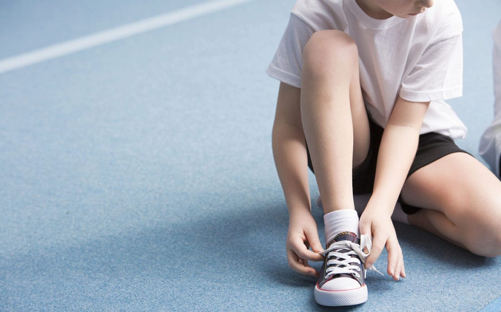 Child with type 1 diabetes tying his shoe. Treatment is received by pediatric endocrinologist in Idaho Falls and Pocatello, Dr. Joshua Smith.
