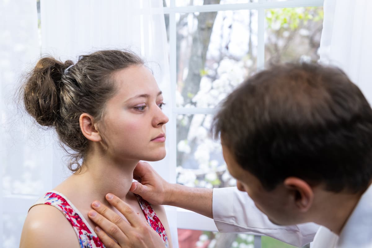 doctor checking a patient's thyroid.
